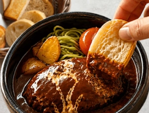 シチューハンバーグにパンをつけている画像